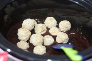 Mixing meatballs into the sauce for Crockpot Jelly BBQ Meatballs @ bestwithchocolate.com