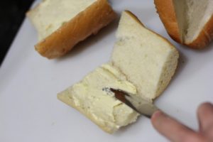 Spreading butter for Cheesy Garlic Bread @ bestwithchocolate.com
