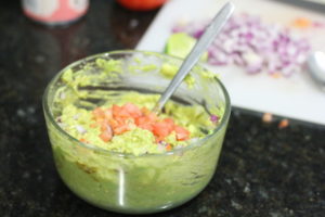 Adding tomatoes to Guacamole @ bestwithchocolate.com