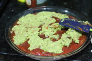 Layering guacamole over refried beans for Five Layer Dip @ bestwithchocolate.com