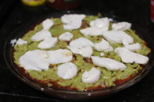 Layering sour cream over refried beans for Five Layer Dip @ bestwithchocolate.com