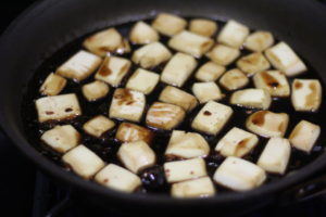 Tossing tofu with sauce for Honey Sesame Tofu @ bestwithchocolate.com