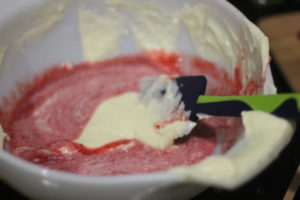 Mixing strawberry puree into cheesecake batter for Strawberry Lemonade Cheesecake Bars @ bestwithchocolate.com