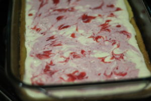 Swirling batter for Strawberry Lemonade Cheesecake Bars @ bestwithchocolate.com