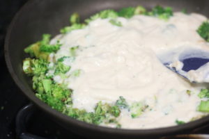 Mixing alfredo sauce into the broccoli for Broccoli Alfredo Stuffed Shells @ bestwithchocolate.com