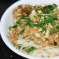 thai peanut chicken in a bowl over rice noodles