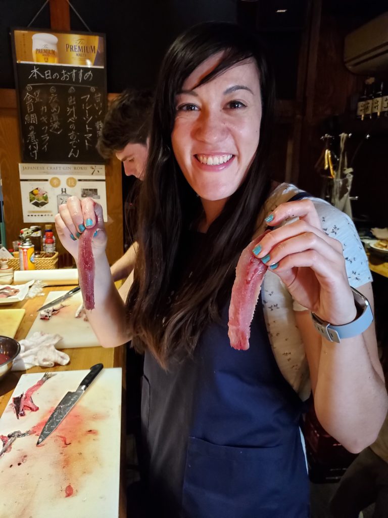 Women holding freshly filleted sardine during Japan travel