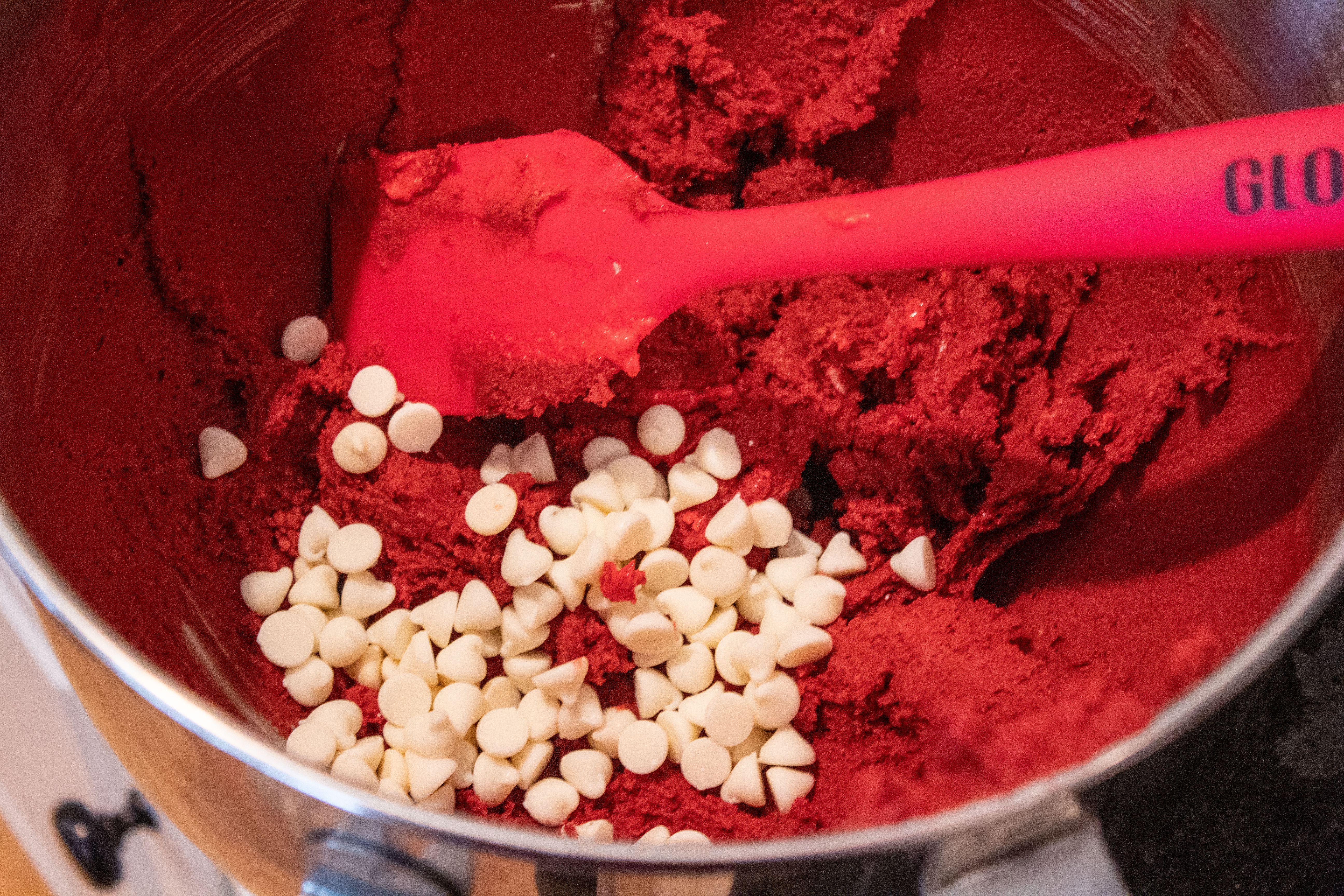 Mixing white chocolate chips into dough for Red Velvet Cookies @ bestwithchocolate.com