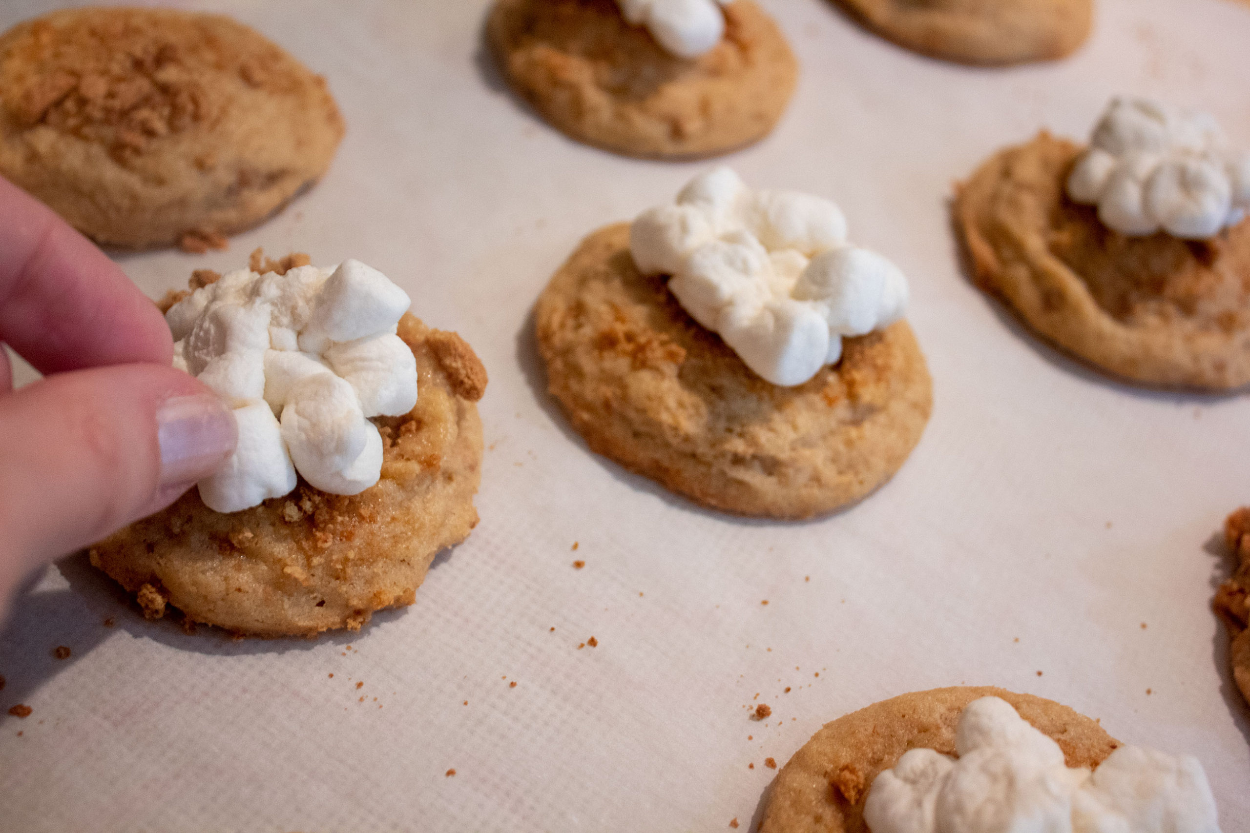 Adding marshmallows to top of freshly baked S'mores Kiss Cookies @ bestwithchocolate.com