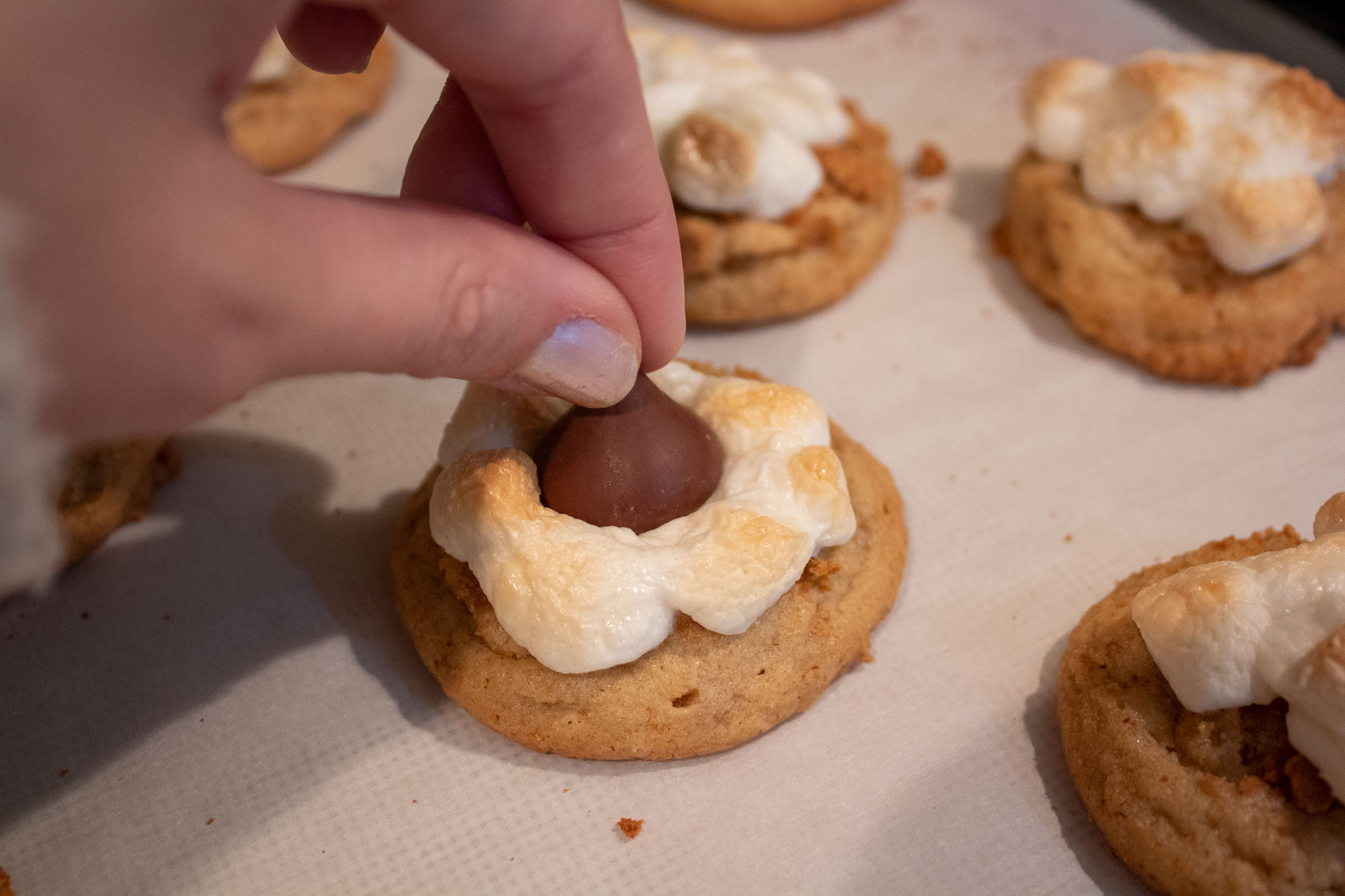 Pressing kisses into freshly baked S'mores Kiss Cookies @ bestwithchocolate.com