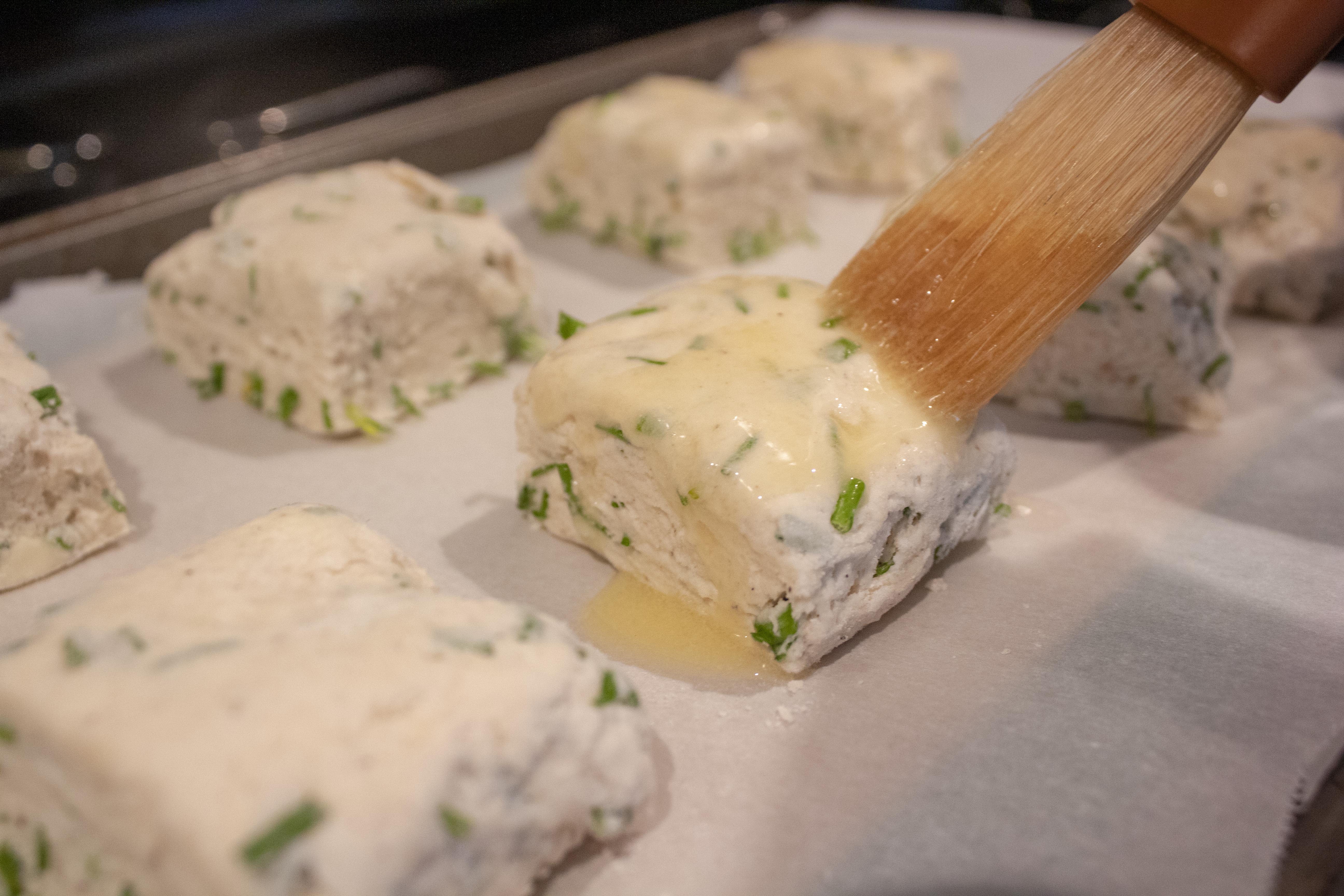 Brushing butter on Sour Cream and Chive Biscuits @ bestwithchocolate.com