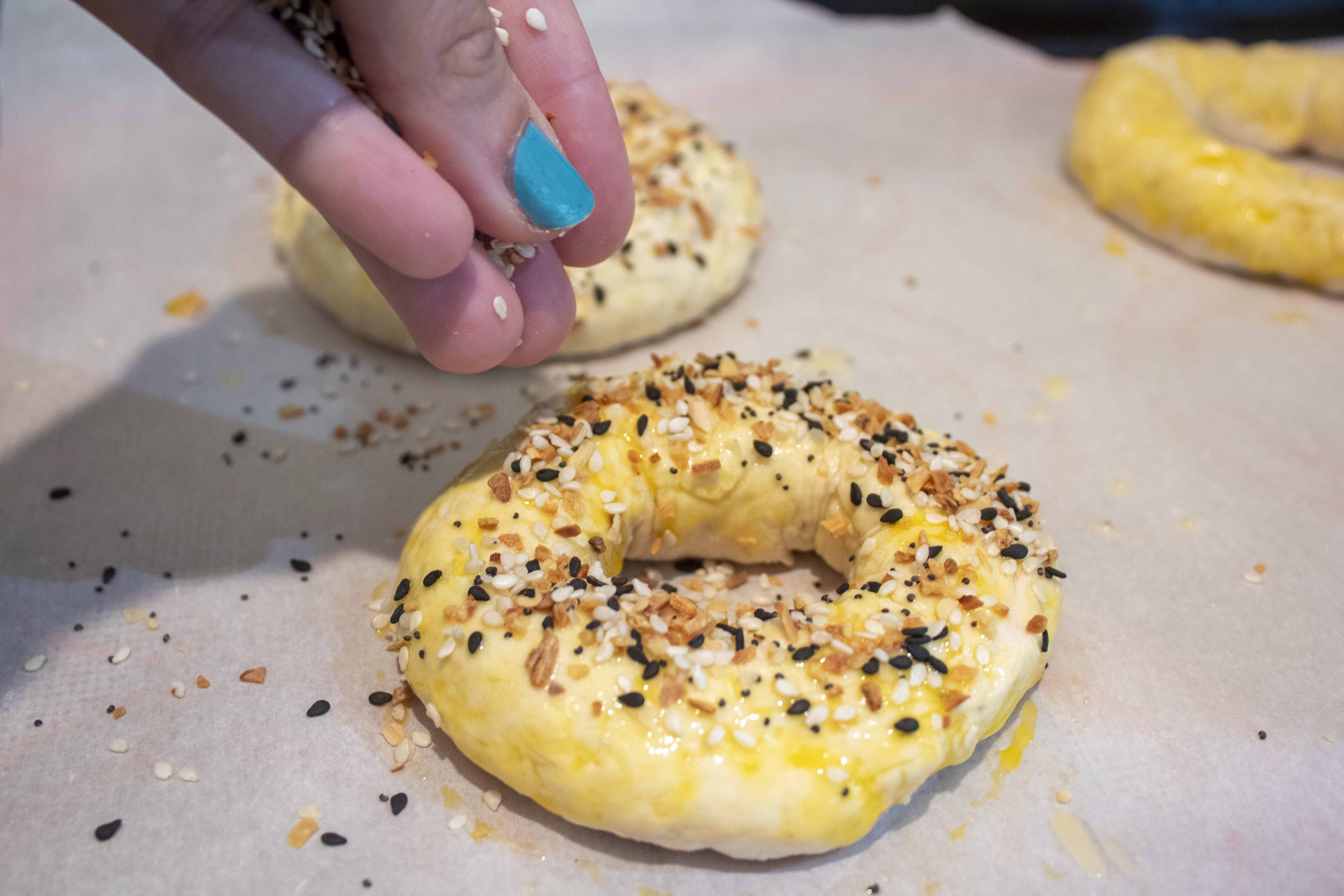 Topping bagels with everything seasoning for Quarantine Bagels @ tipsychochochip.com