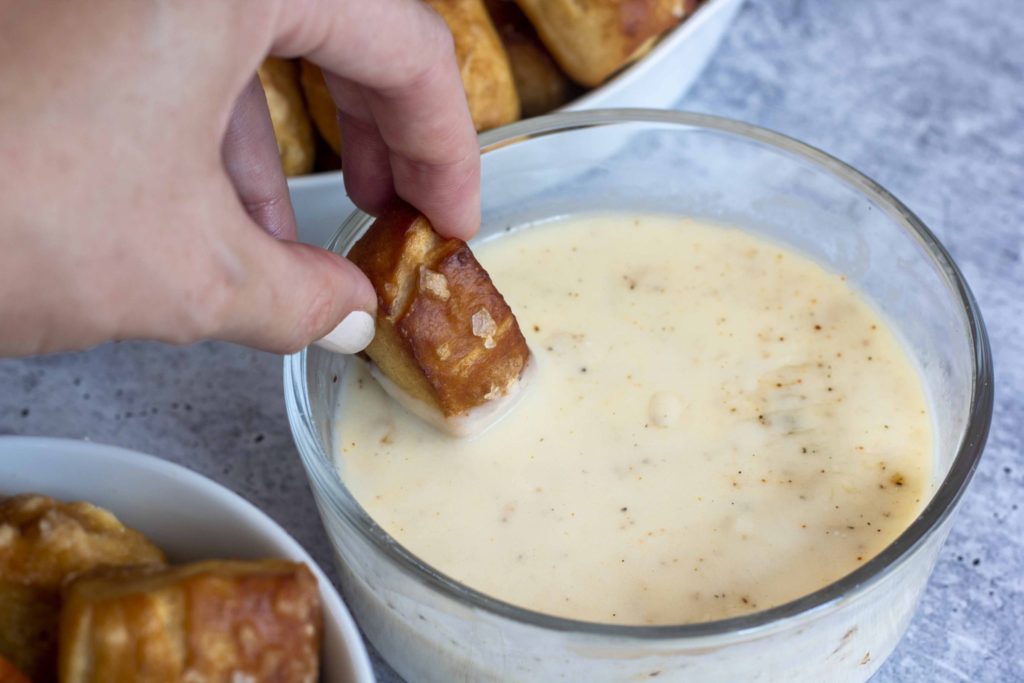Dipping Pretzel into White Cheddar Cheese Sauce @ bestwithchocolate.com