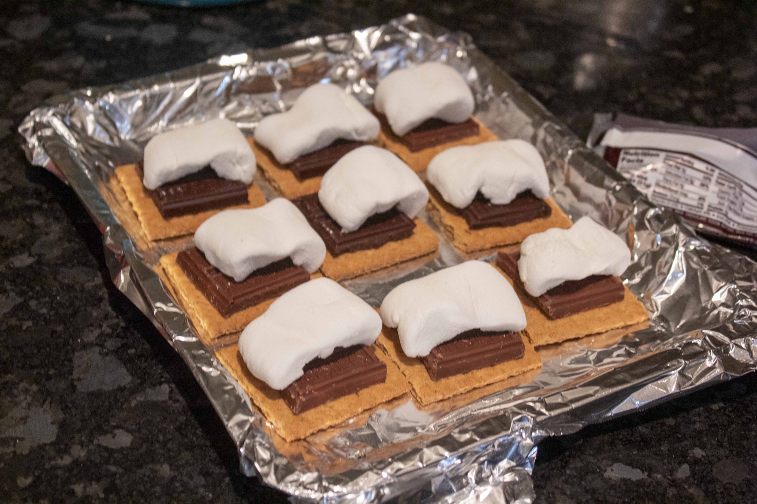 Topping s'mores with marshmallows to go into the oven