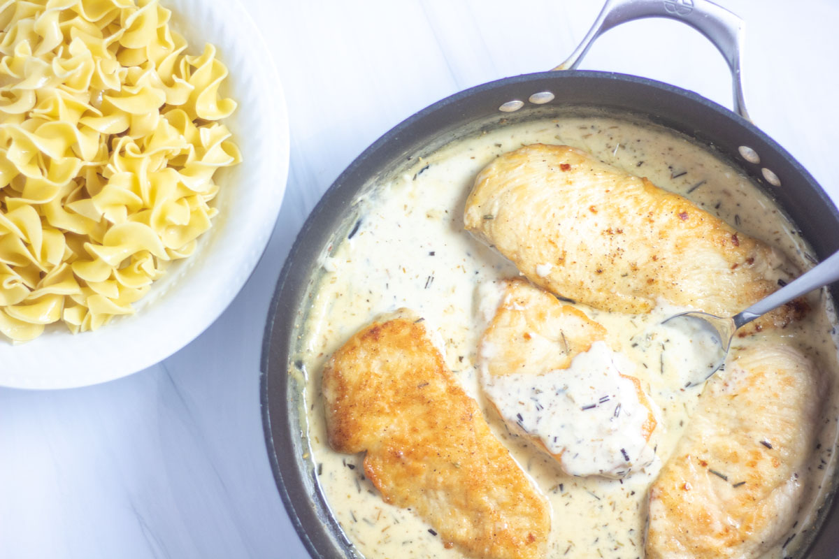 Rosemary cream chicken in the pan with butter noodles