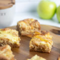 Apple cake drizzled with honey and apples in the background