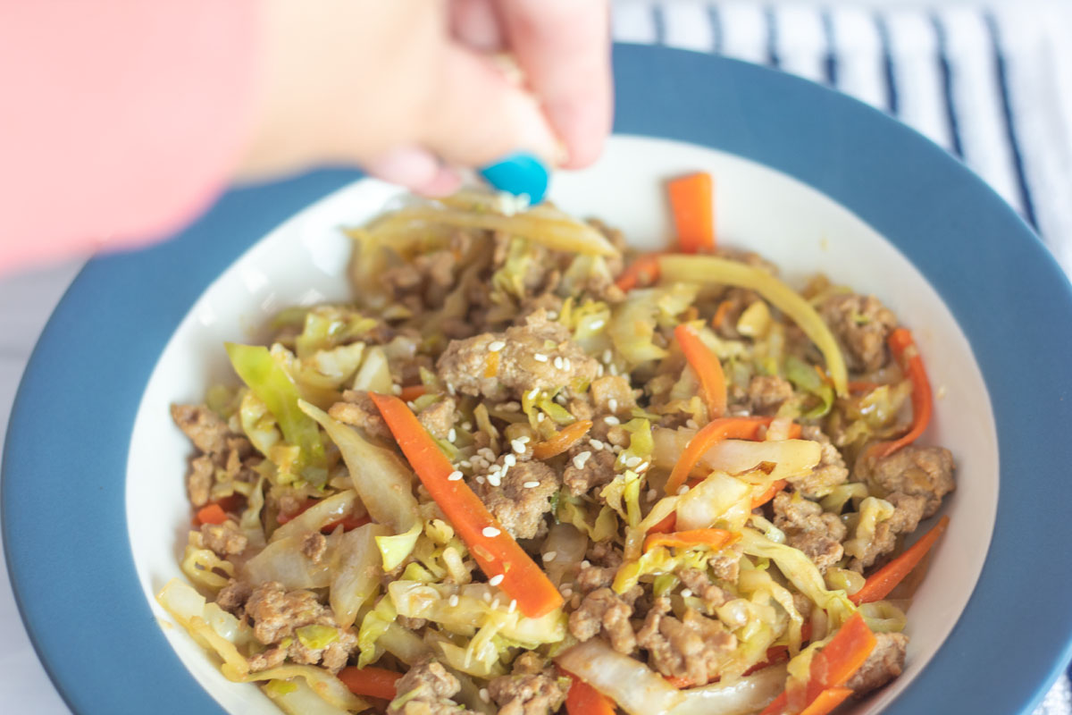 adding sesame seeds topping to eggroll in a bowl