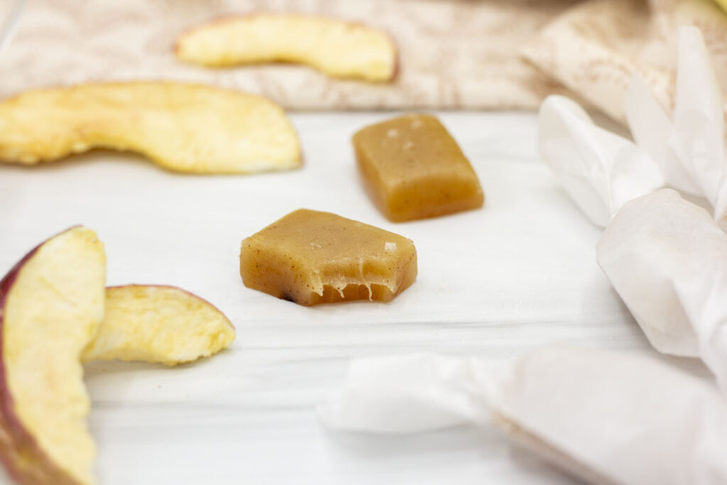 Apple cider caramels amidst wrapped caramels and dehydrated apple slices