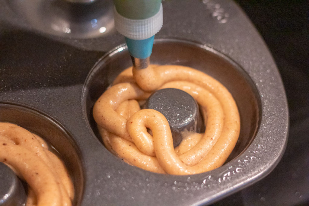 Adding doughnut batter to doughnut pan