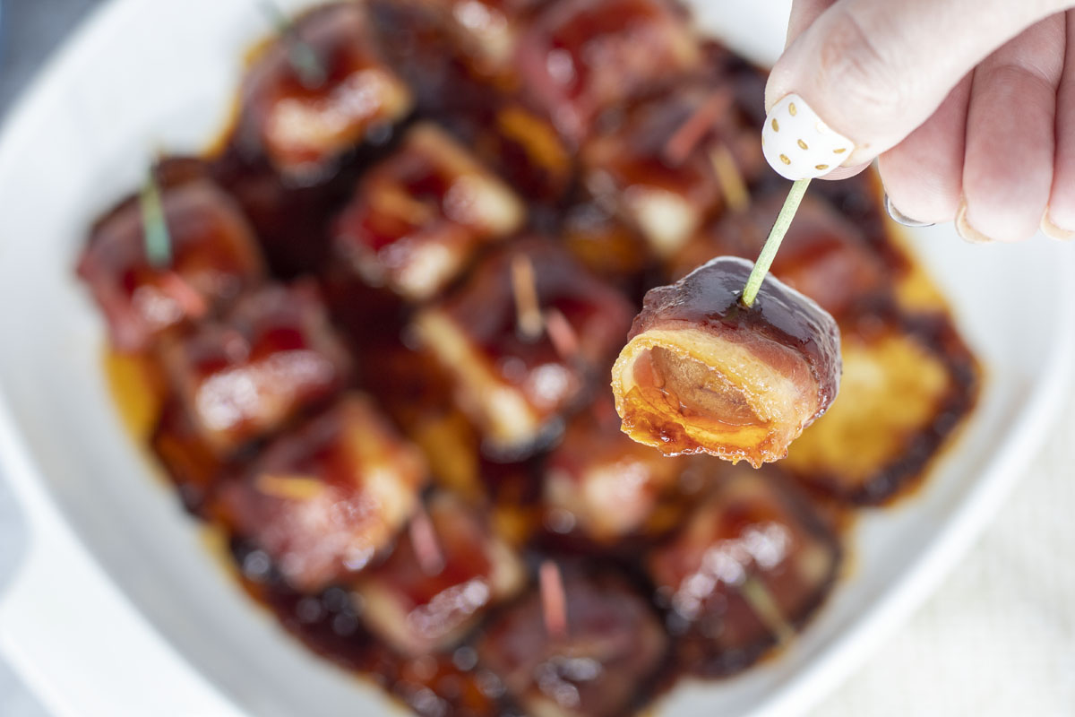 picking up a bacon wrapped waterchestnut from the pan