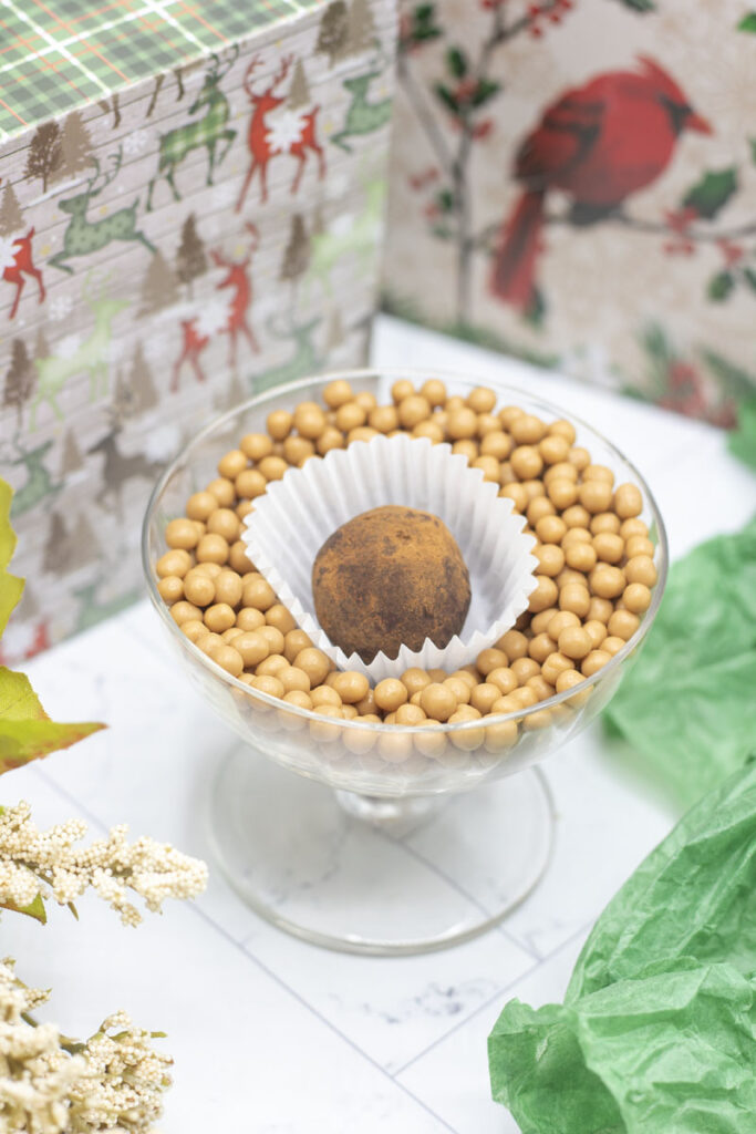 A caramel crunch bailey's truffle in a bowl of caramel crunch balls