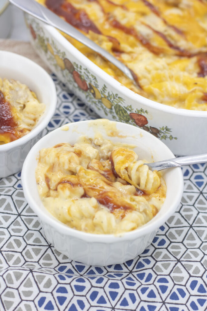 Spoon lifting out pasta of individual cup of pulled pork mac and cheese