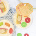 Vanilla dirt cups with a beach scene: teddy grahams on a rainbow sour strip beach towel surrounded by lifesavers