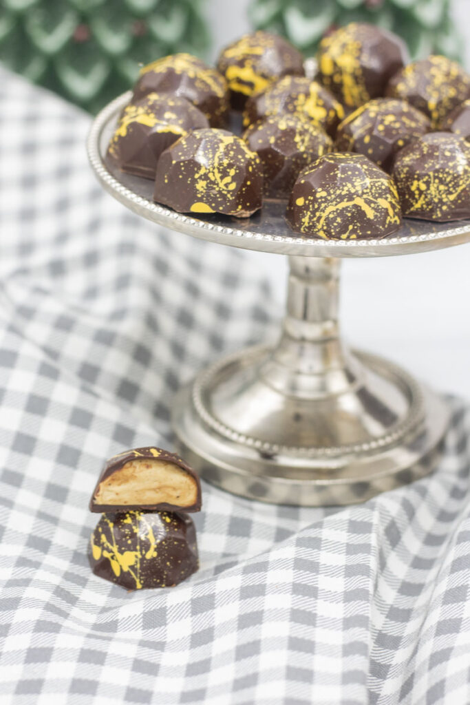 A cut biscoff truffle in front of a platter of tempered chocolate truffles