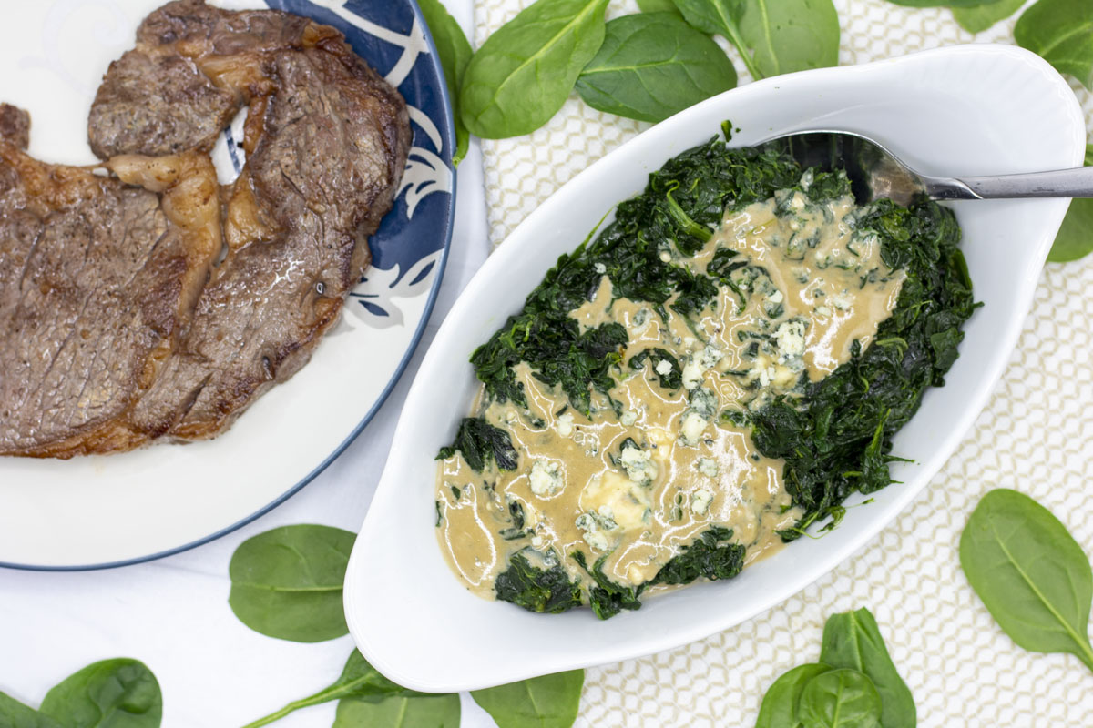 View of blue cheese creamed spinach next to steaks;