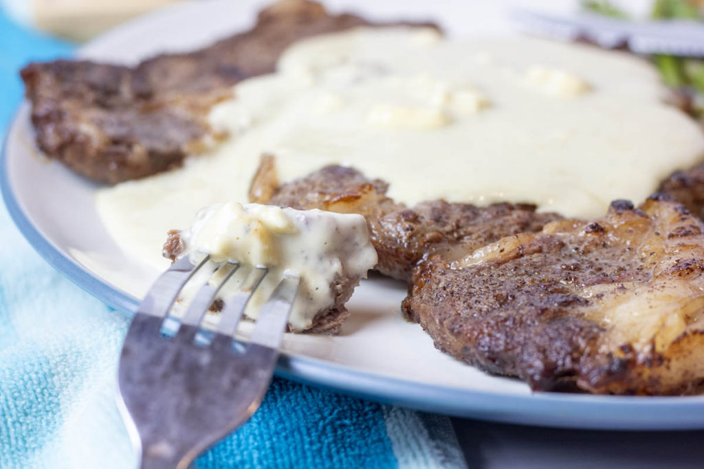 Sliced steak on a fork with blue cheese sauce