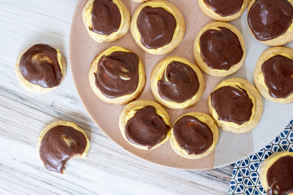 Boston cream cookies on a plate scattered around