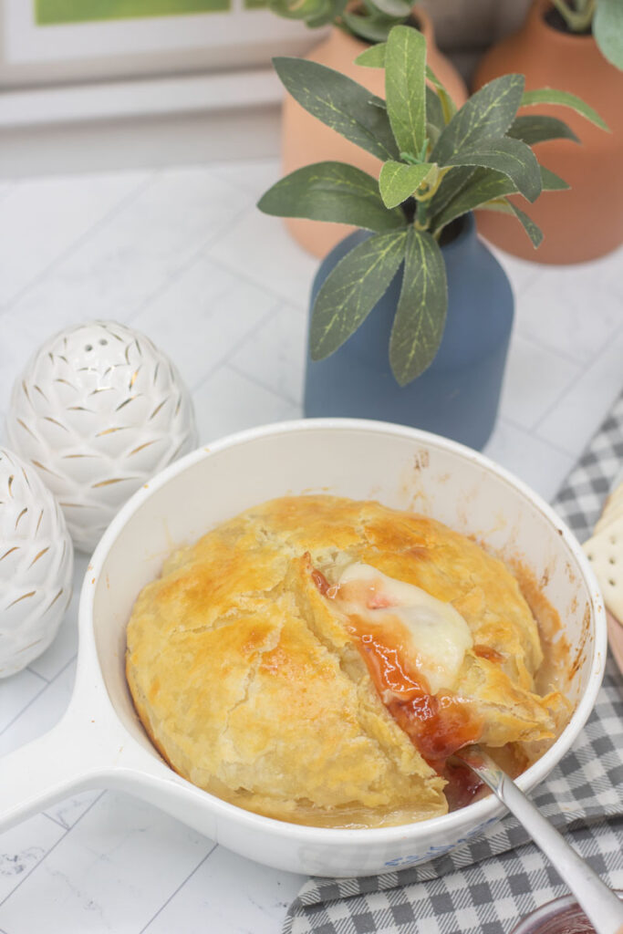 Cutting into baked brie en croute with raspberry jam