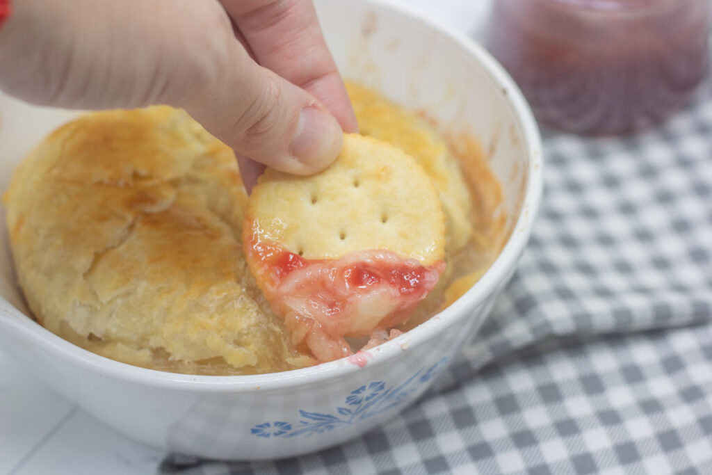 Cracker scooping up baked brie