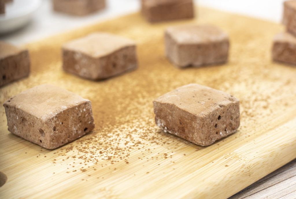 chocolate brownie batter marshmallows on a cutting board with cocoa powder