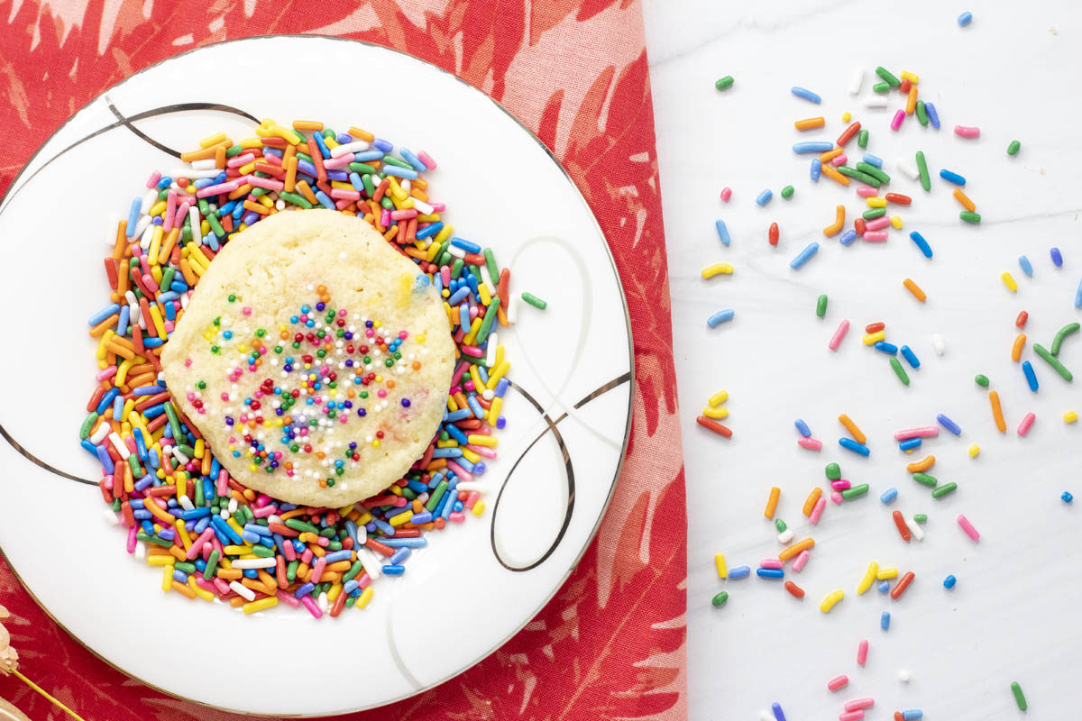butter sprinkle cookie on a plate of sprinkles