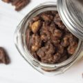 slow cooker candied cinnamon nuts in a jar with lid askew