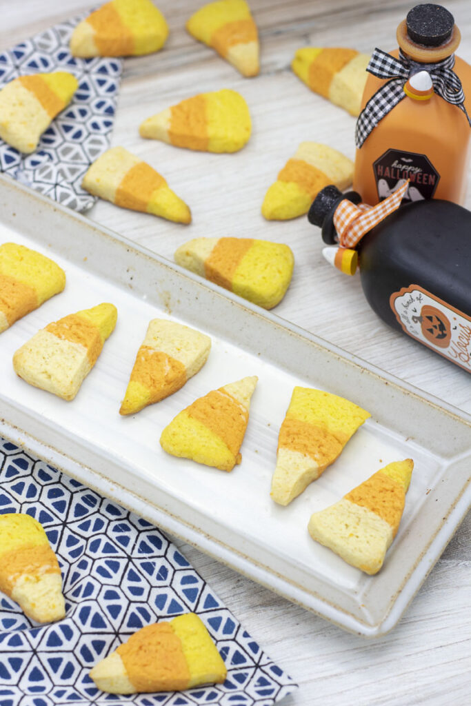 Orange sugar cookies in the shape of candy corn arranged in a neat line on a plate 