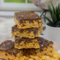 Caramel cornflake bars stacked on a pile of cornflakes