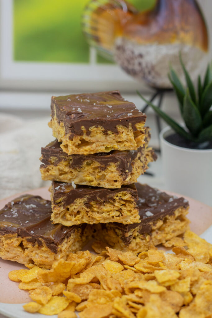 Caramel cornflake bars stacked on a pile of cornflakes
