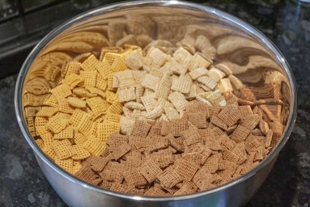 Three different kinds of chex in a bowl to make party chex mix