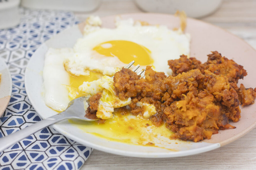 A fork scooping egg yolk and chorizo potato hash