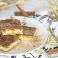 Churro cheesecake bars stacked on a plate sprinkled with cinnamon