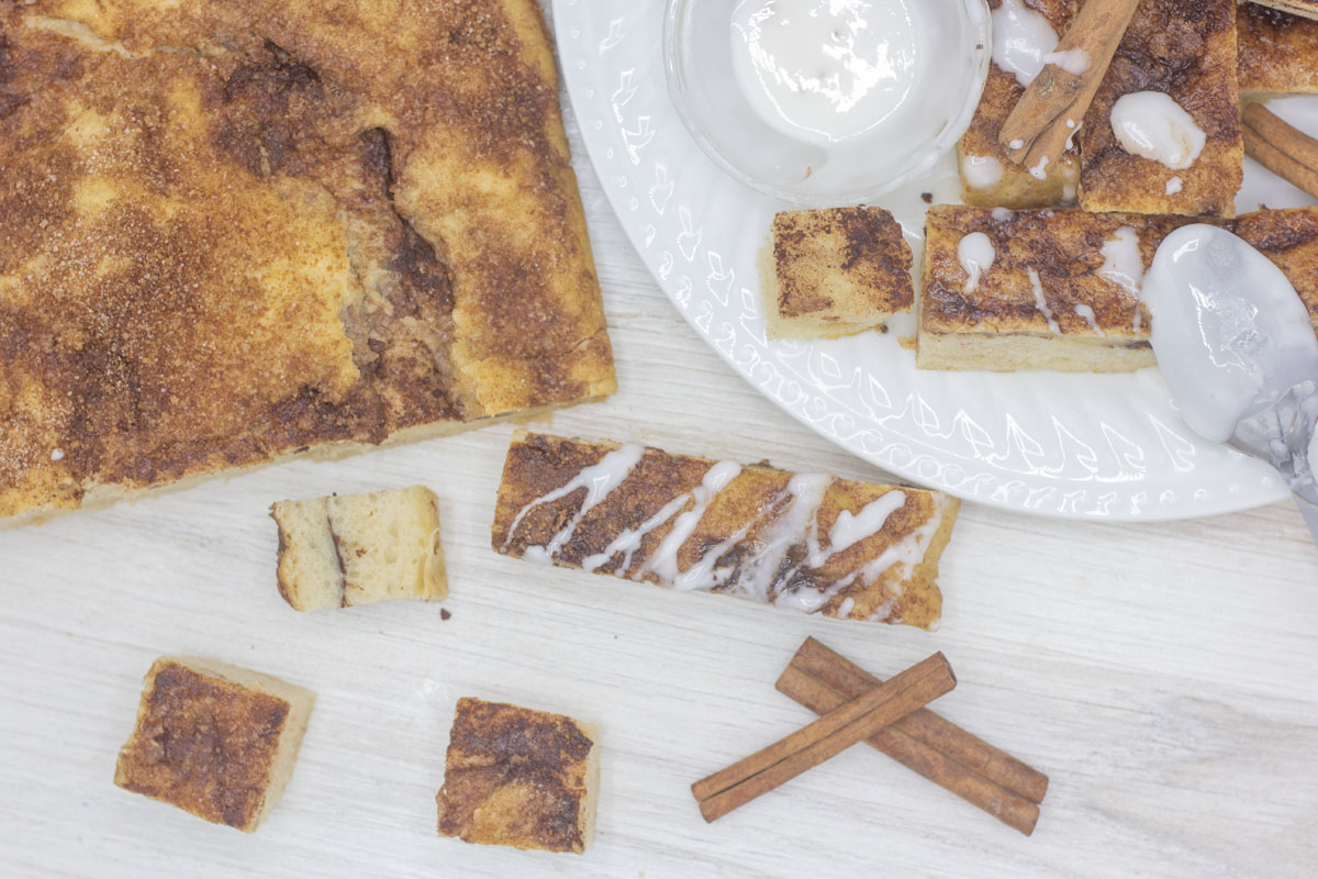 Loaf of focaccia beside breadsticks and cubed cinnamon focaccia