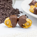 Two chocolate-dipped cookie dough pretzel bites standing beside each other
