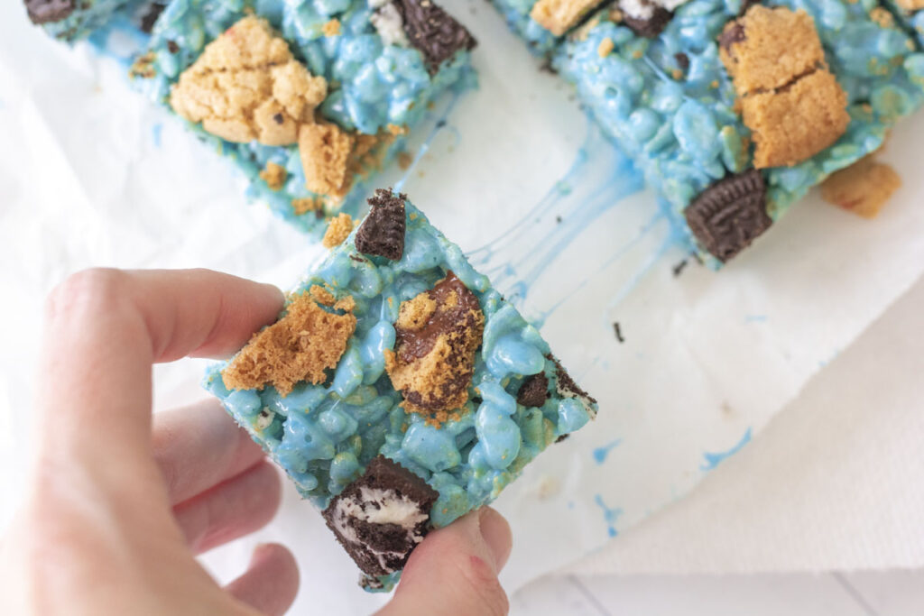 Pulling a gooey marshmallow blue rice krispie square away from the other cookie monster rice krispie treats