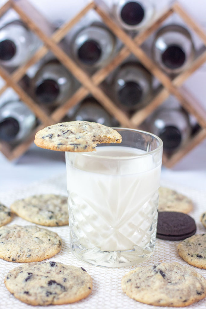 cookies and cream cookies around a glass of milk with one perched on top