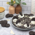 Cookies and cream pie on a table with oreos scattered around