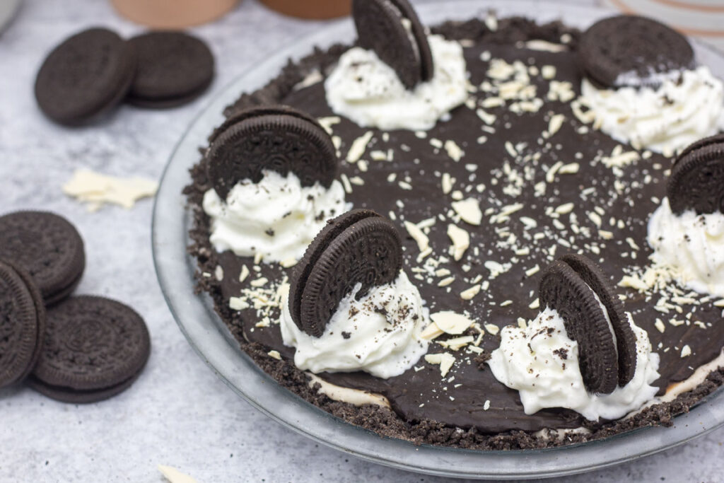 Close up of cookies and cream pie decorated with whipped cream, oreos, and shaved white chocolate