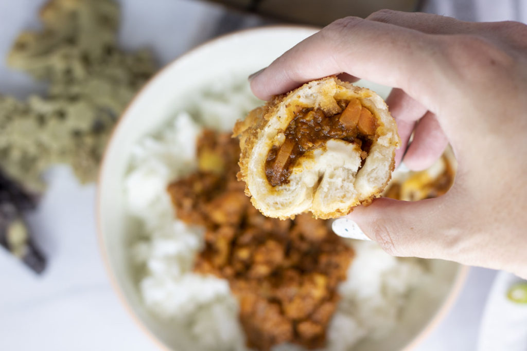 hand holding japanese curry bun cut in half