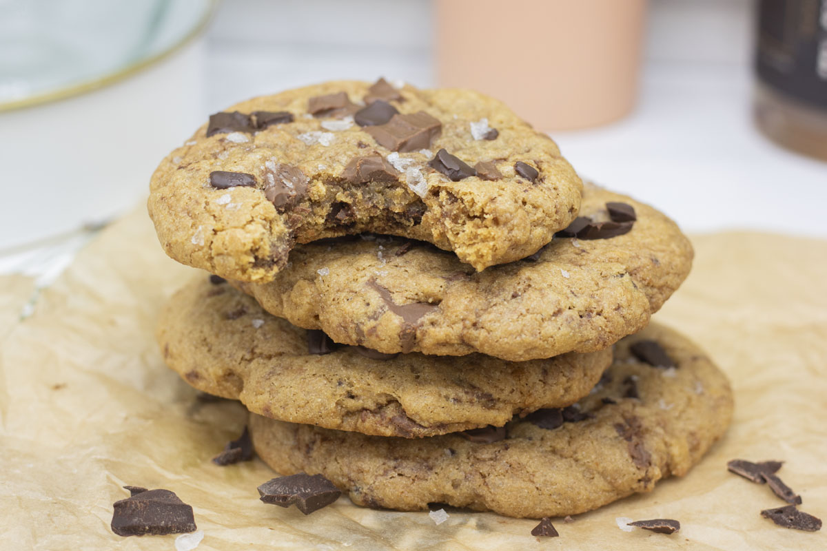 Tower of supersized salted chocolate chunk cookies with a bite taken out of the top one